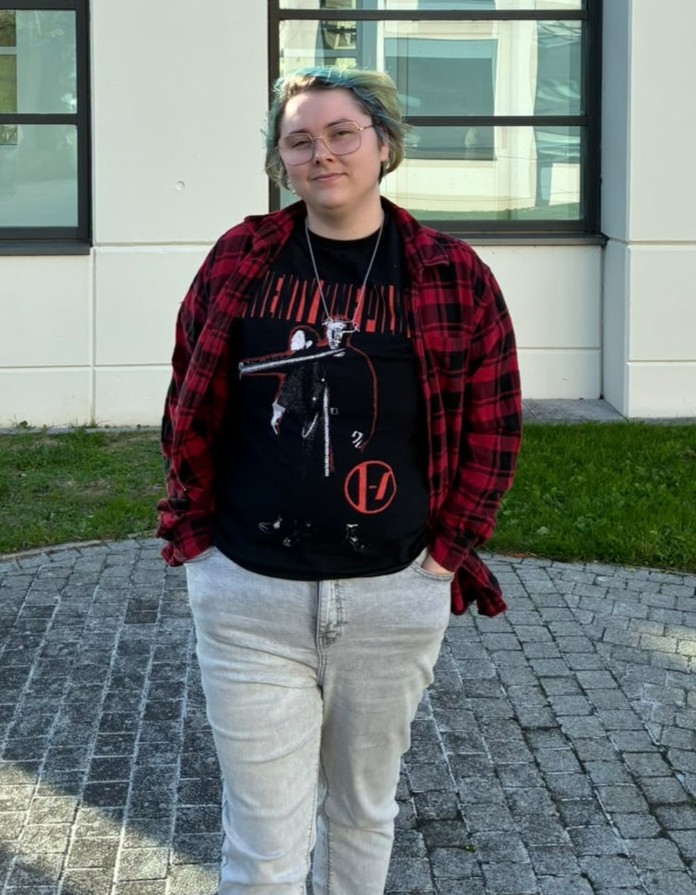 Ashton is standing outside and smiling at the camera.