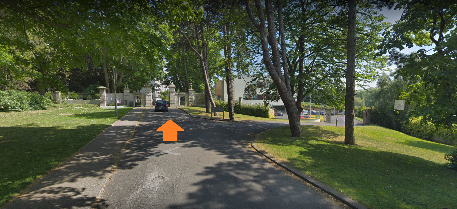 View of driveway to Marino Institute with gate in the distance, orange arrow indicates to move towards gate