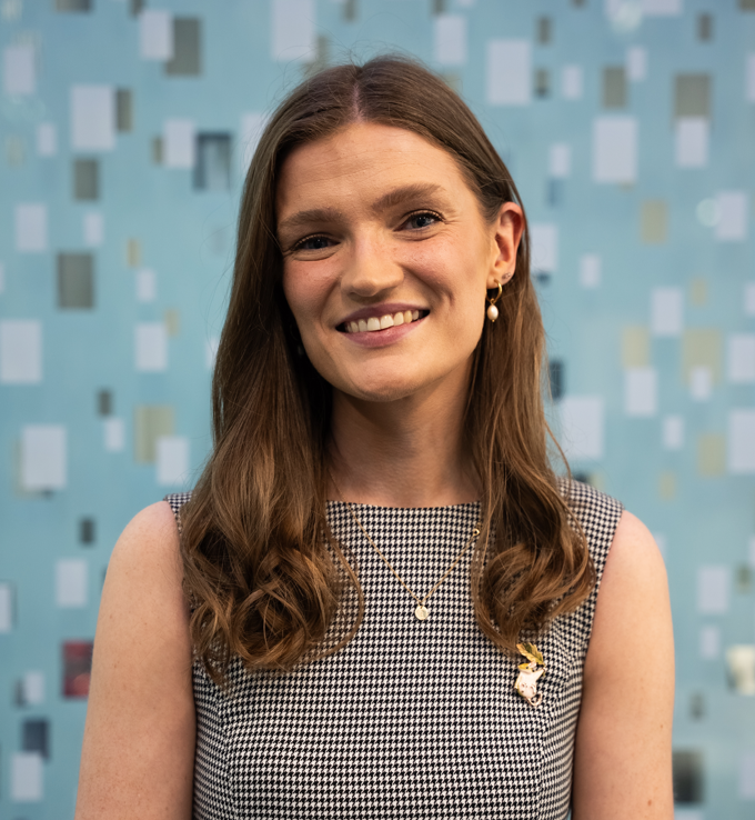 Photograph of Banba Fitzgerald smiling at the camera wearing a black and white dress. 