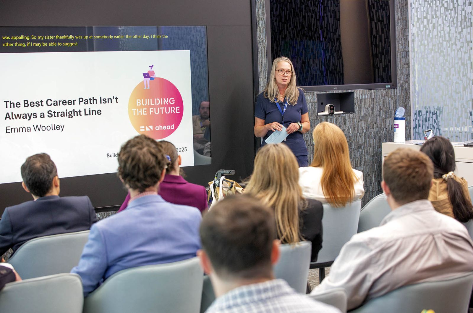 Photograph shows presenter in front of students and graduates in the workshop room.